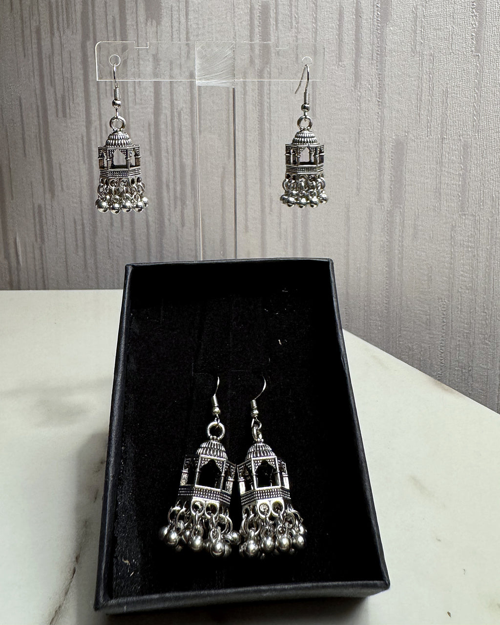 Jharokha oxidised silver jhumka earrings on an acrylic stand and in a black gift box