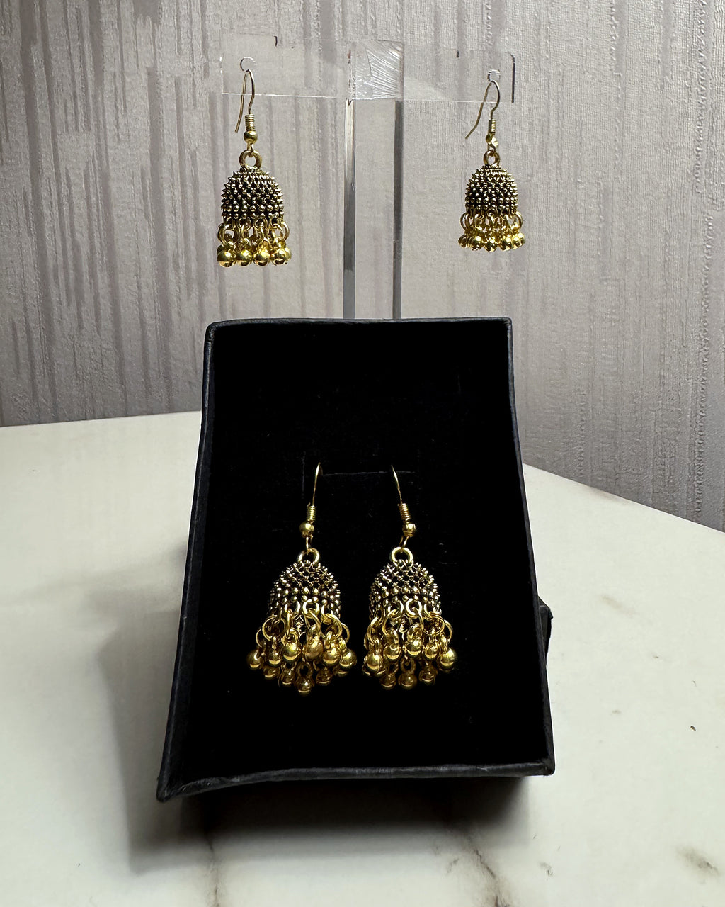 Zarreen antique gold jaali jhumka earrings on an acrylic stand and in a black gift box