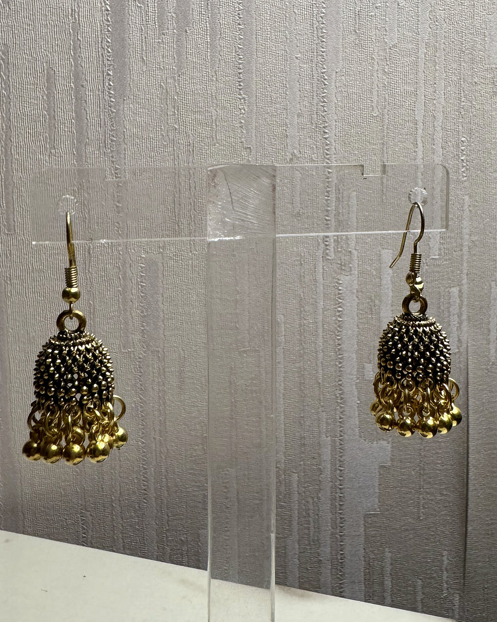 Close-up of Zarreen antique gold jhumka showing the jaali dome and ghungroo bead fringe