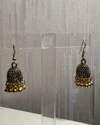 Close-up of Zarreen antique gold jhumka showing the jaali dome and ghungroo bead fringe