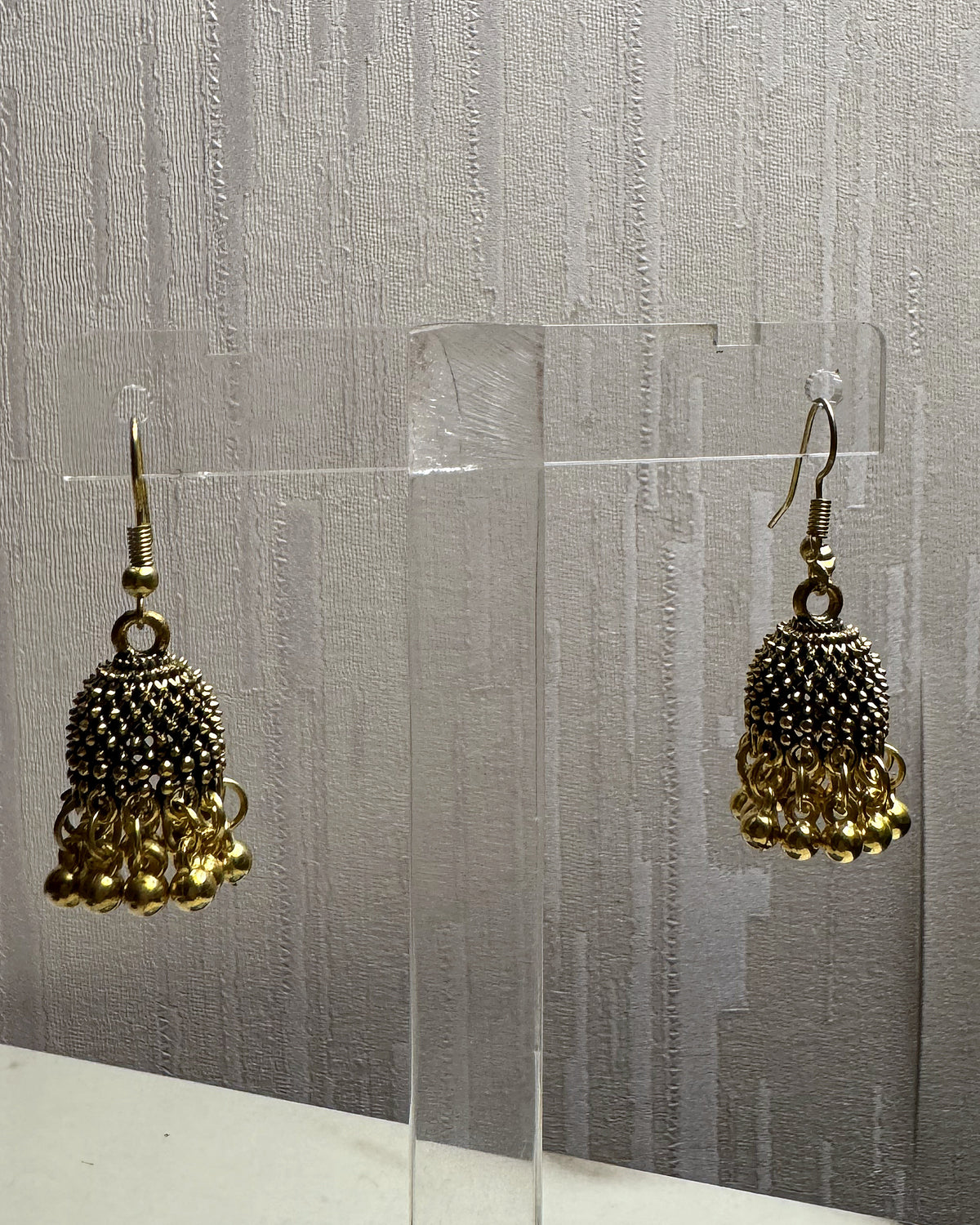 Close-up of Zarreen antique gold jhumka showing the jaali dome and ghungroo bead fringe